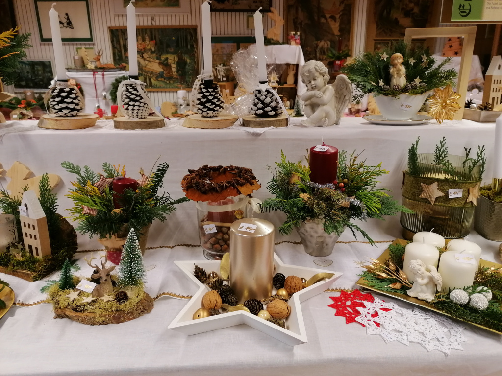 Weihnachtliche Gestecke und Kerzen auf einem Adventbasar-Tisch