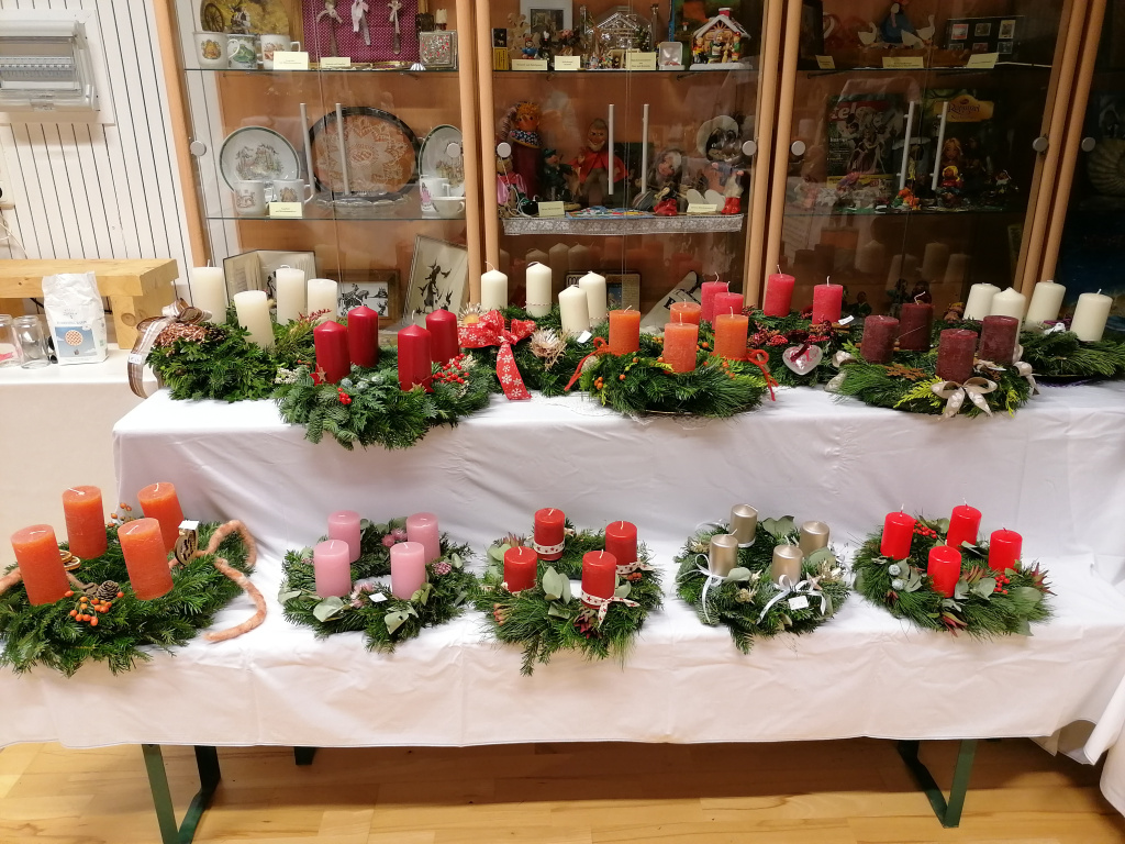 Tisch mit Adventkränzen in verschiedenen Farben und Größen