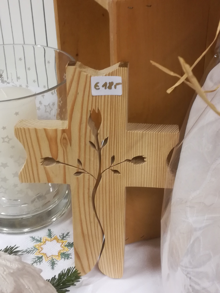 Holzkreuz mit eingeschnitztem Zweigmotiv auf Tischdeko
