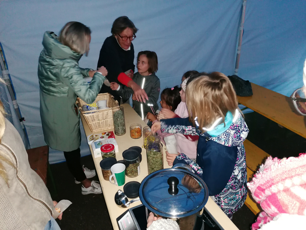 Kinder und Erwachsene an einem Tisch mit Gläsern und Kräutern