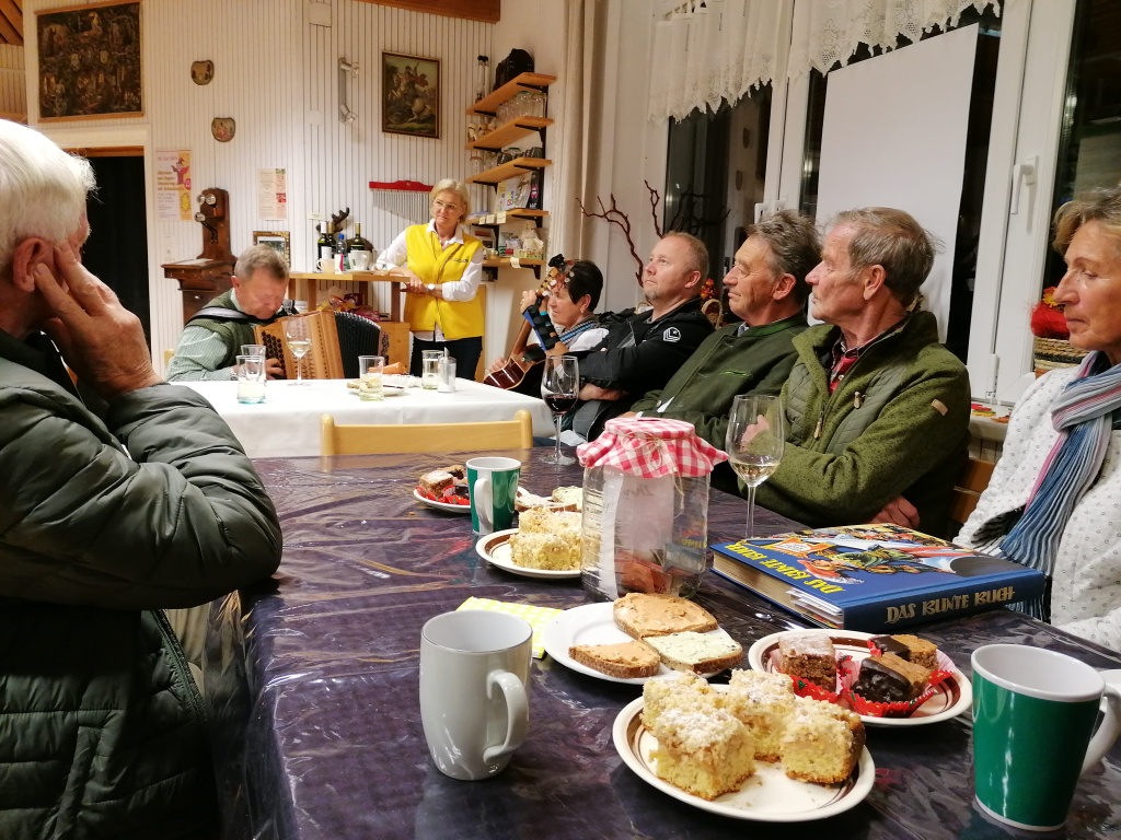 Menschen sitzen bei Kaffee und Kuchen in gemütlicher Runde
