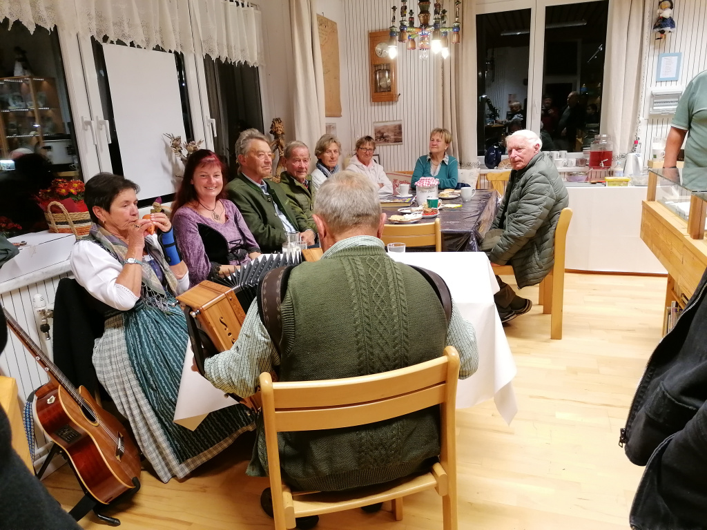 Menschen in Tracht musizieren und sitzen an einem Tisch