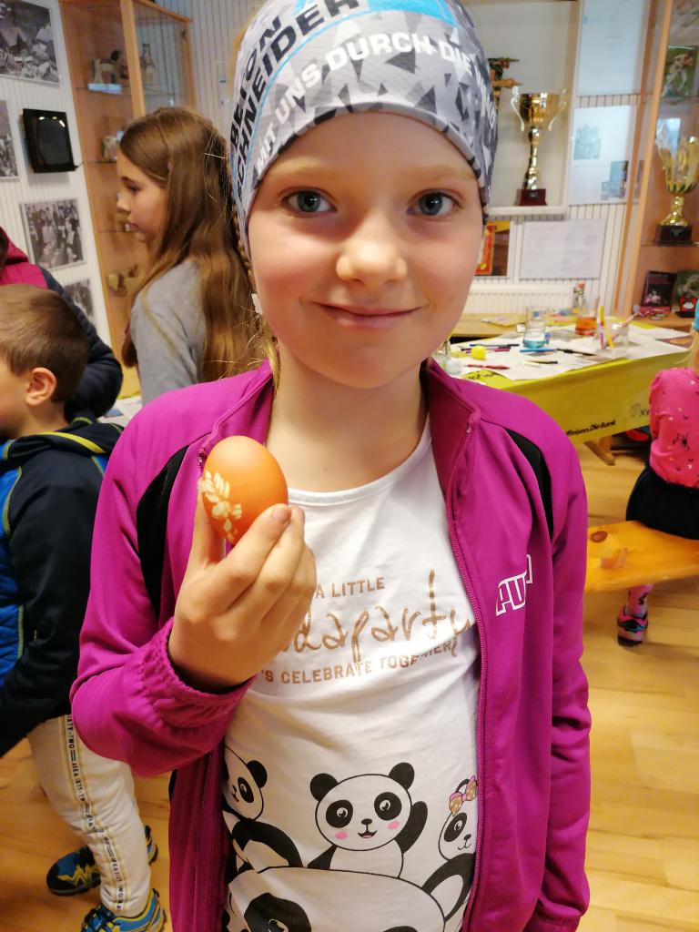 Mädchen zeigt gefärbtes Osterei im Museum