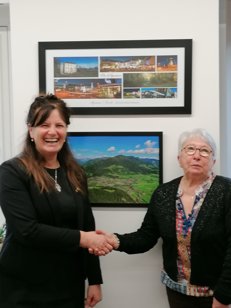 Zwei Frauen geben sich die Hand vor Wandbildern
